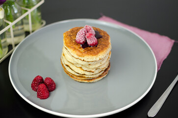 Stack of American pancakes with blueberry jam and fresh raspberries