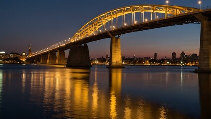 Fototapeta premium Illuminated bridge at sunset over a city with water reflections.
