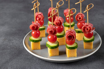 Canape with cherry tomatoes, sausage, cheese and cucumbers