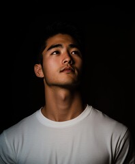 Obraz premium 暗い背景で上を見上げる男性のポートレート