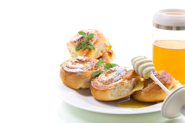 Baked goods. Sweet buns with cottage cheese filling and honey in a plate isolated on a white background