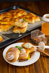 Pastries. Sweet buns with cottage cheese filling and honey in a plate on a wooden table