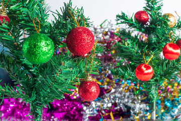 Close-up of a Christmas tree decorated with sparkling red and green baubles for the holiday season.