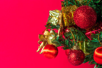 Festive Christmas tree with ornaments on vibrant red background with copy space your text, close up.