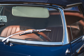 Windscreen and wiper with leather interior in a background of a classic car on a vintage car show.