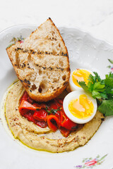 A hearty breakfast with a boiled egg, sweet pepper, fried piece of bread and chickpeas.