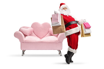 Santa claus holding shopping bags and dancing in front of a sofa