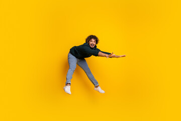 Young man in mid-air against bright yellow background radiating fun and energy