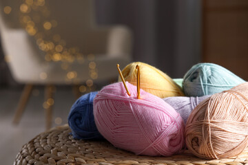 Knitting material. Skeins of soft yarn and crochet hooks on wicker surface indoors, closeup