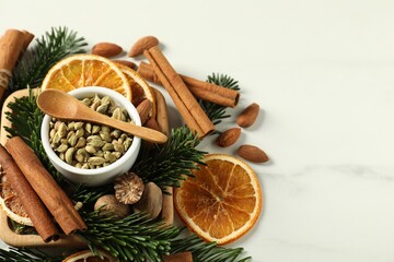 Different spices, dried orange slices and fir tree branches on white marble table, above view with space for text. Christmas season