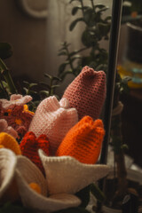 A vibrant bouquet of crocheted flowers displays shades of pink, yellow, and white, nestled among green yarn leaves, against a softly blurred background, highlighting their intricate details.