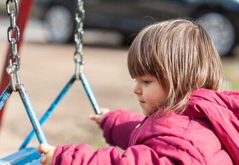 A portrait of a little girl holding a swing in the park