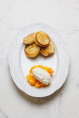 Appetizing cheese pancakes with mango and ice cream on a large white plate