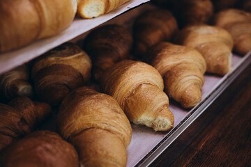 Delicious croissants on the store showcase of the bakery house, close up.