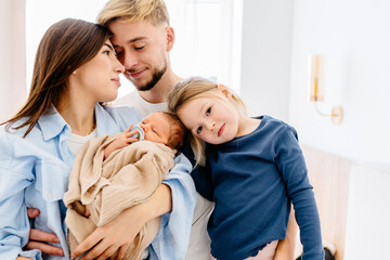 Loving family with newborn baby and sibling in cozy setting