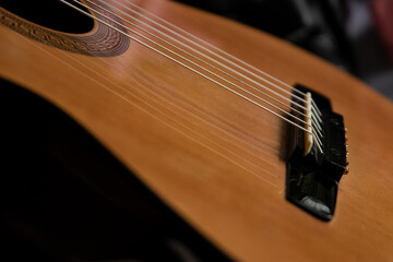 Fototapeta premium A close-up of an acoustic guitar body focusing on the strings, soundhole, and bridge. The warm wooden tone of the instrument and soft bokeh create a cozy and musical atmosphere.
