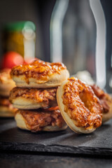 Mini pizza bagels on cutting board on black table.