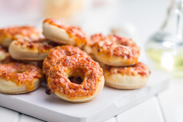 Mini pizza bagels on cutting board on white table.