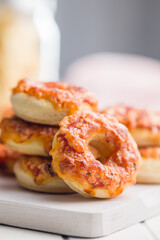 Mini pizza bagels on cutting board on white table.
