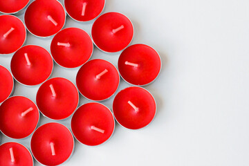 Red, new and unused tealight candles, designed on a white surface with copy space