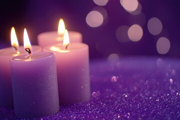 Three lit candles on a purple surface