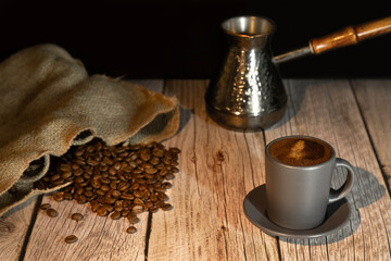 Coffee, coffee beans and a turk on a wooden background.