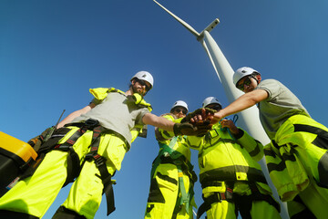 A group of  workers in high-visibility gear joyfully high-fives each other after completing their...