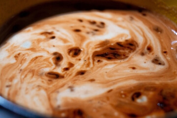 a close-up of thick, swirling coffee in a pot, mixing dark and light hues, creating a mesmerizing marbled effect, inviting and warm in appearance.