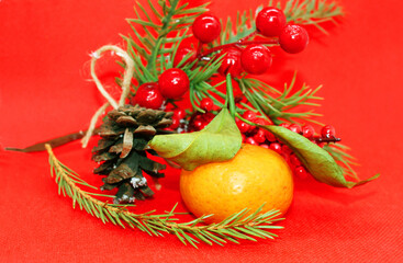 A spruce branch with a pine cone and a tangerine with leaves on a beautiful background, holiday, Christmas.