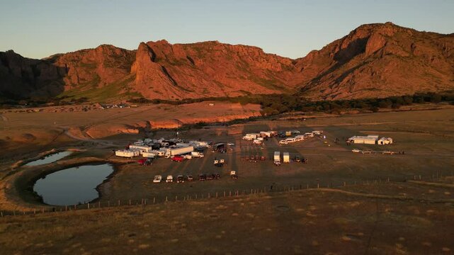 horizontal drone video of Durango dessert with mountains in sunset with small lake and trucks at John Wayne ranch 