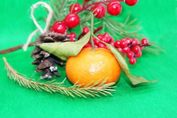 A spruce branch with a pine cone and a tangerine with leaves on a beautiful background, holiday, Christmas.