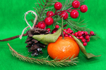 A spruce branch with a pine cone and a tangerine with leaves on a beautiful background, holiday, Christmas.