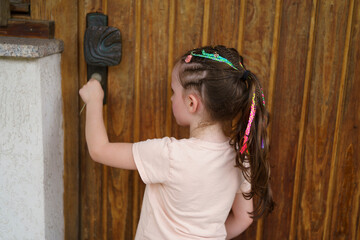 Little cute girl with dreadlocks standing near wooden door. Healthy active child concept
