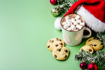 Fototapeta premium A warm Christmas setting featuring chocolate chip cookies and hot chocolate with marshmallows on a green background