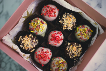 Various cake pops, pastries decorated with white and dark chocolate, nuts in a gift box