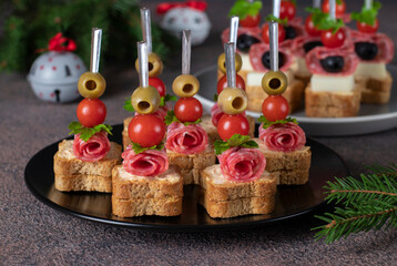 Canape with cherry tomatoes, sausage, cheese and olives