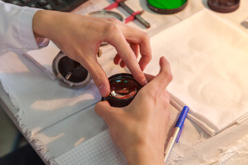 An engineer assembles a camera lens by hand.