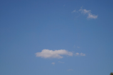 A vast blue sky stretches out with a few fluffy white clouds drifting lazily, creating a serene and tranquil atmosphere that evokes a sense of peace and openness.