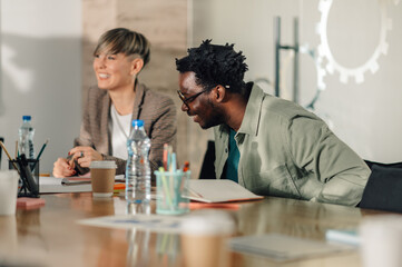 Coworkers laughing during meeting in modern office