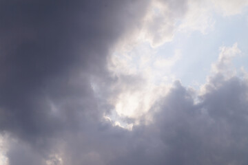 a dramatic sky filled with varying shades of gray clouds, illuminated by patches of light breaking through, creating a moody and contemplative atmosphere