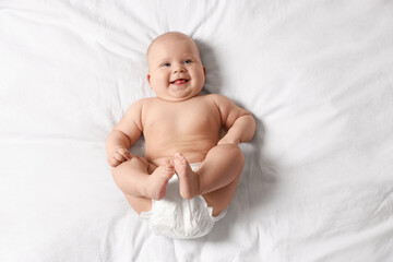 Cute little baby in diaper on bed, top view