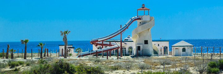 A deserted beach with a white building and a red slide