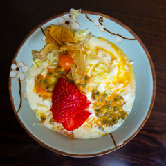 Tropical fruity mousse dessert from maracuya pulp with cream garnished with chocolate flakes, strawberry and physalis
