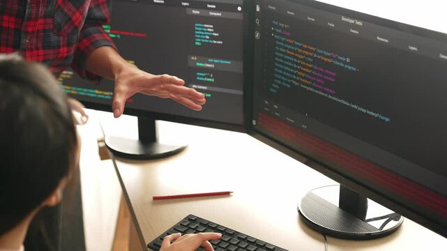Back end or software developer manager supervising his team on new application program development on debugging and solving complex code algorithms on monitor. Burgeoning