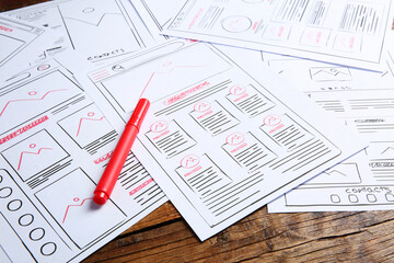Developing UI design. Sketches of website wireframes and felt pen on wooden table, closeup