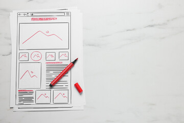 Developing UI design. Sketches of website wireframes and felt pen on white marble table, top view....
