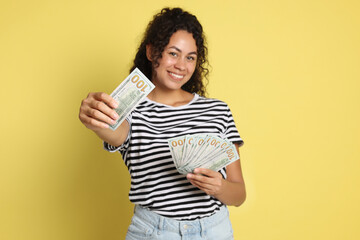 Happy woman with dollar banknotes on yellow background