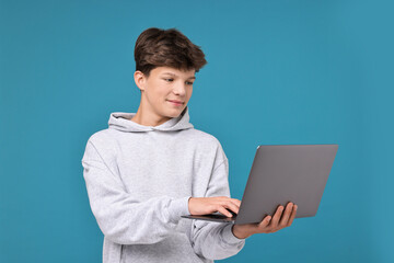 Teenage boy with laptop on light blue background