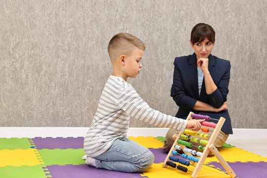 Psychologist observing little boy playing in autism treatment center. Space for text