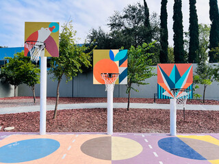 Three colorful painted basketball hoops for children in a row from tall to short. 